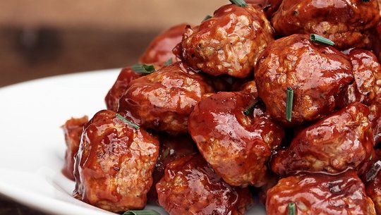 Plate stacked with meatballs, sprinkled with chives