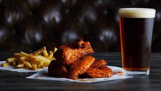Image of fries, buffalo wings and a beer