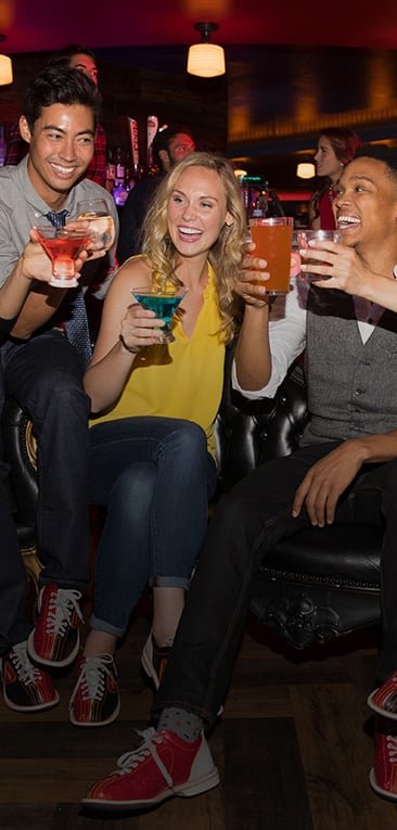 Three people holding up cocktails in celebration