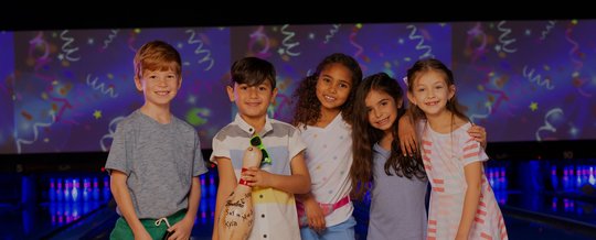 5 kids posing on the lanes holding a signable bowling pin