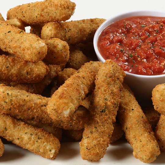 Pile of mozzarella sticks on a plate near a bowl of marinara sauce