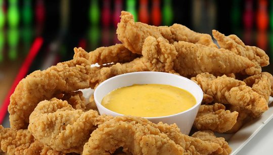 Chicken tenders around a bowl of honey mustard
