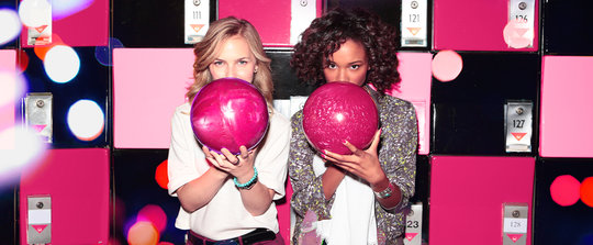 two women holding pink bowling balls