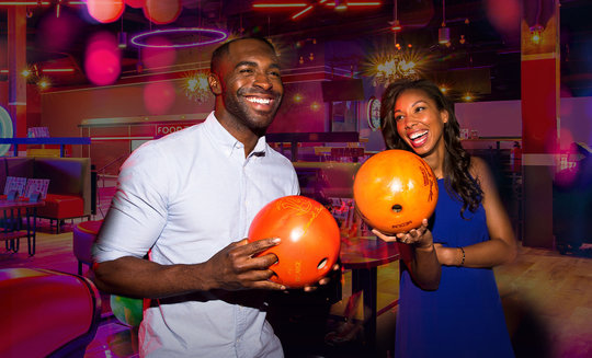two people holding bowling balls