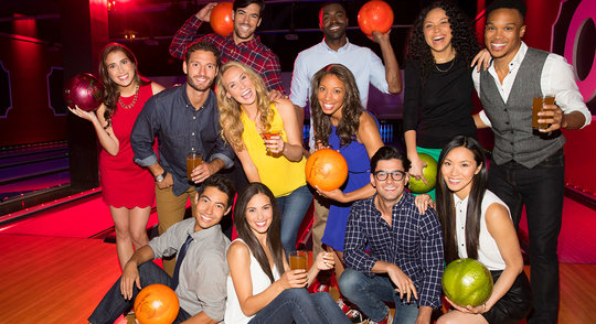 a group of bowlers holding bowling balls, laughing with drinks