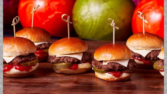 cheese burger sliders in a row with bowling balls in the background