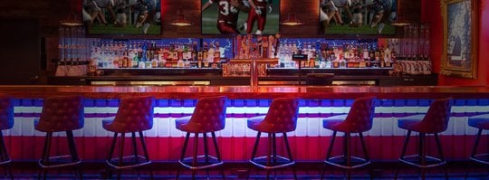 sports bar with red bar chairs, lit in neon