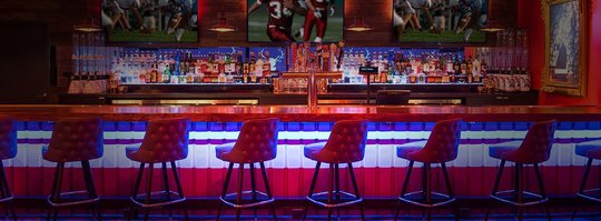 sports bar with red bar chairs, lit in neon