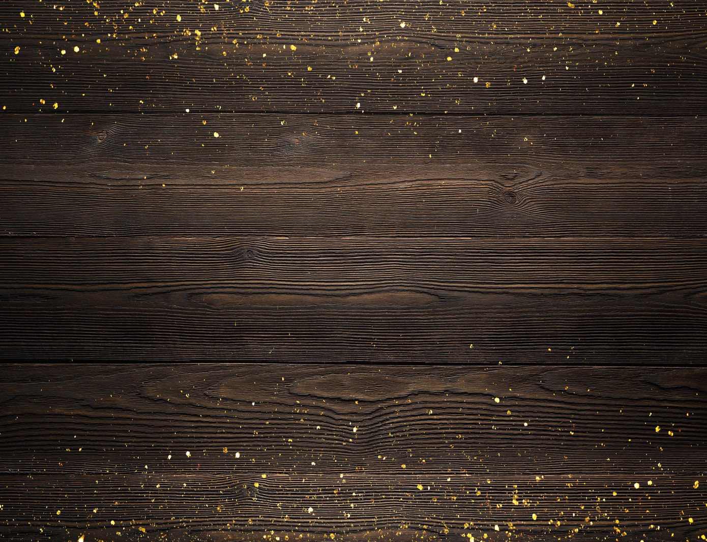 Gold glitter on top of a dark brown wood background