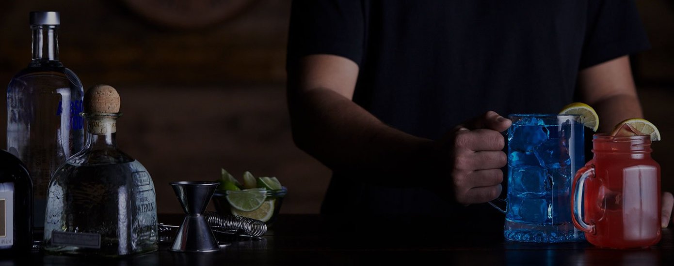 Bartender making cocktails on a table with liquor and bar tools