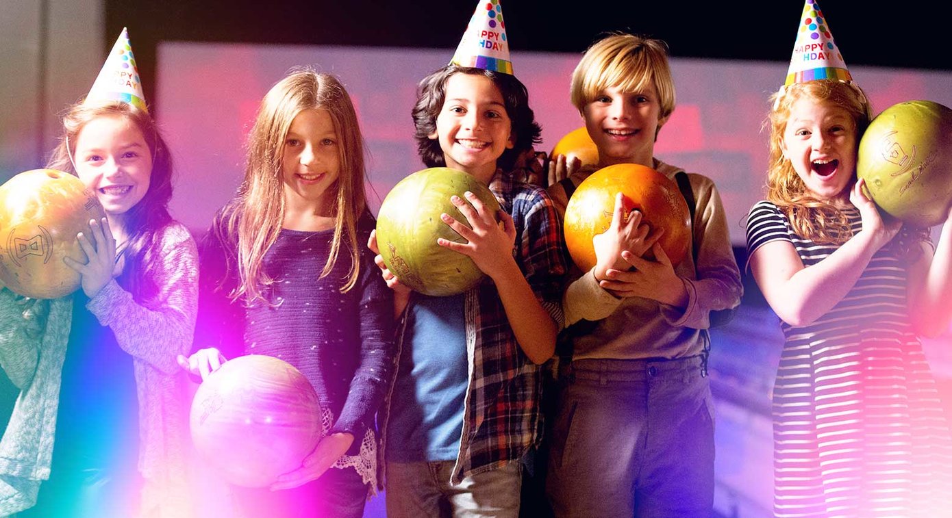Kids in birthday hats holding bowling balls